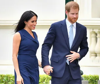 Prince Harry and Meghan Markle hold hands in matching navy outfits during a public appearance in Melbourne.