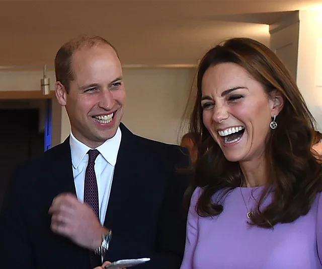Man and woman laughing together at an indoor event.