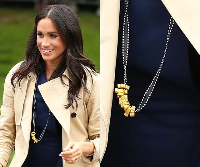 Woman wearing a trench coat and a necklace with painted pasta. Close-up shows detail of pasta-shaped beads.