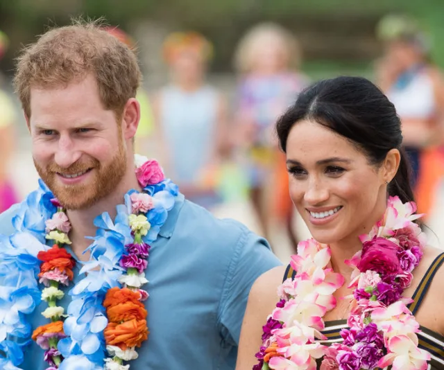 A smiling couple wearing colorful leis, enjoying an outdoor event.