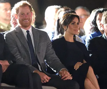 A couple seated at an event, holding hands and engaging with the audience.