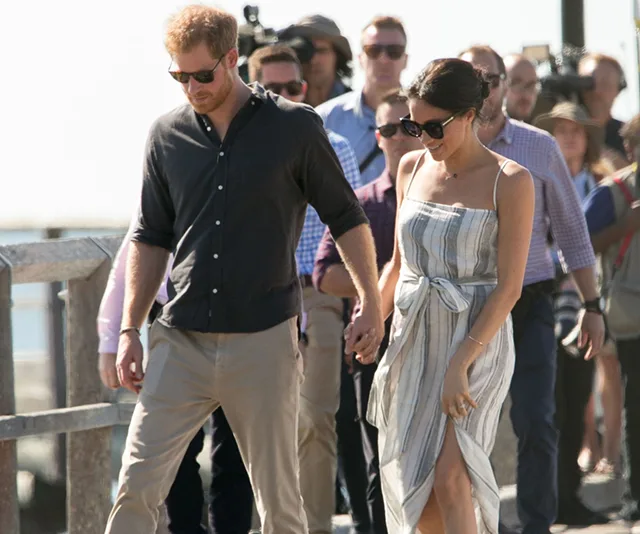 Couple walking outdoors, holding hands, on Fraser Island, surrounded by a group of people.