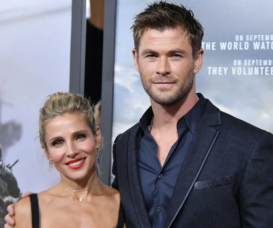 A couple posing together on a red carpet event, both smiling and dressed in formal attire.