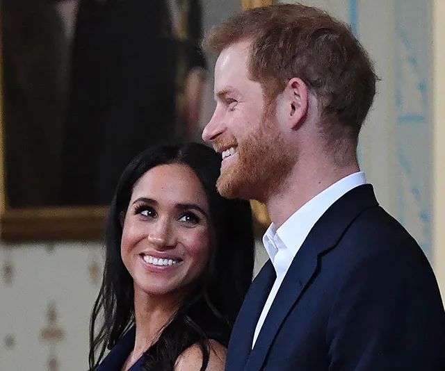 A smiling couple, dressed in dark outfits, looking at each other at a formal event.