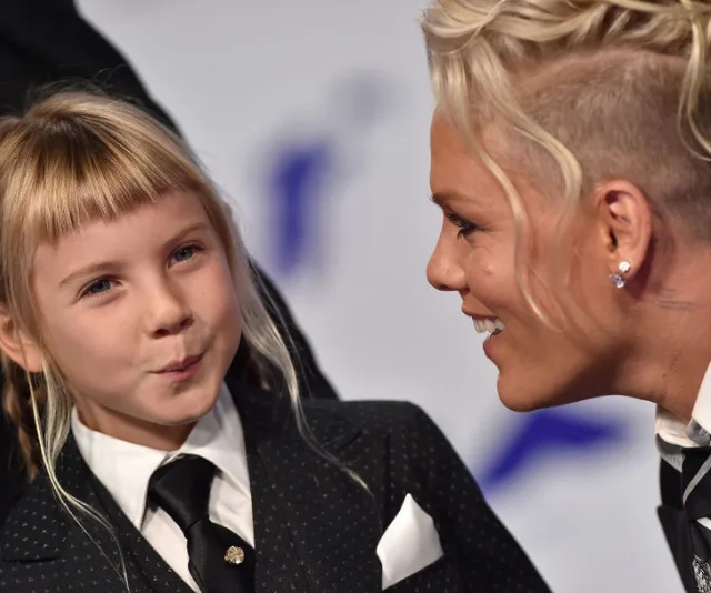 Two people in suits smile at each other warmly at an event.