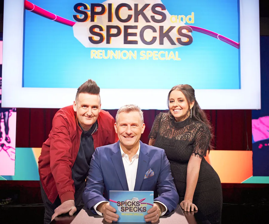 Panelists on stage for "Spicks and Specks Reunion Special," with show logo displayed in the background.