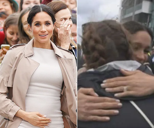 Meghan Markle smiling in a crowd and embracing someone in a hug outdoors.