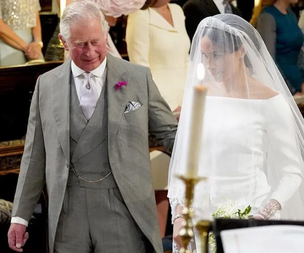 Prince Charles walks with Meghan Markle in a wedding dress at a ceremony.