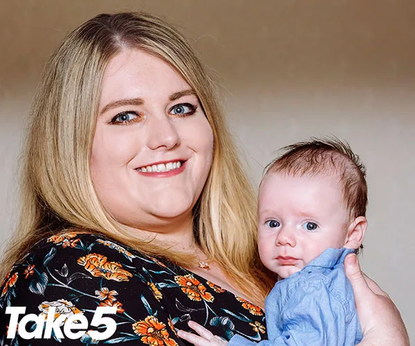 A woman smiling while holding a baby, wearing a floral-patterned outfit, with a "Take 5" logo in the corner.