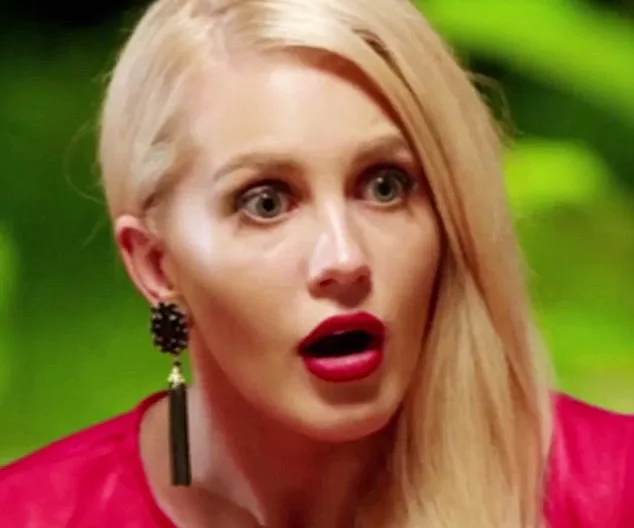 A surprised woman with long blonde hair, wearing bold red lipstick and black earrings, against a blurred green background.