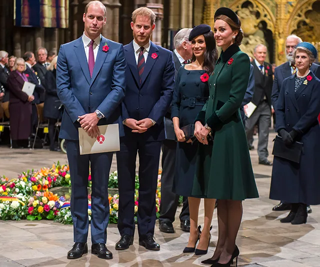 Four individuals stand together at a remembrance event, wearing formal attire with poppy pins.