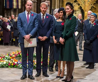 Four individuals stand together at a remembrance event, wearing formal attire with poppy pins.