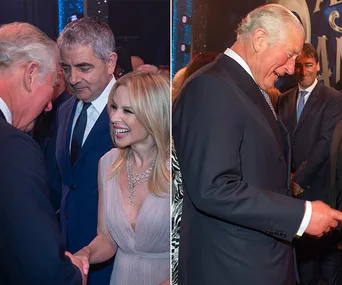 People socializing at an event; a woman smiling and greeting a man in a suit.