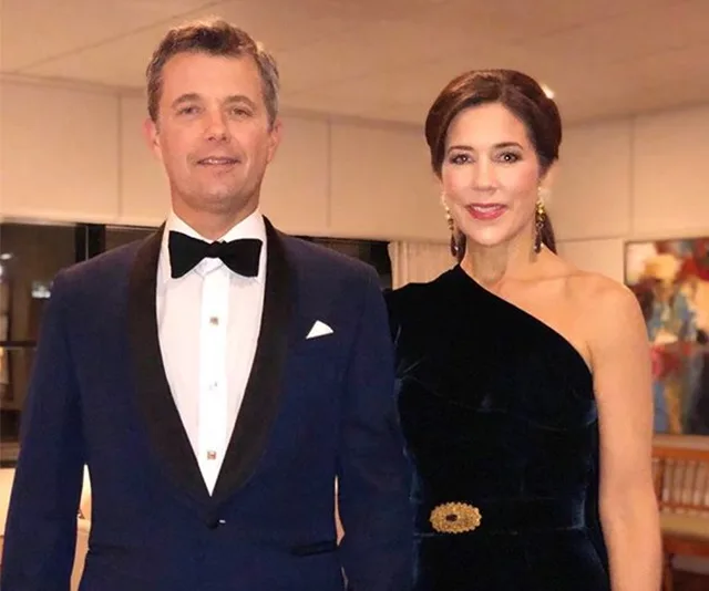 A couple dressed in formal evening wear, standing together and smiling.