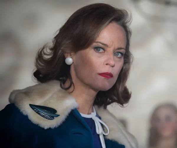 Woman with short hair and blue coat in a serious expression.