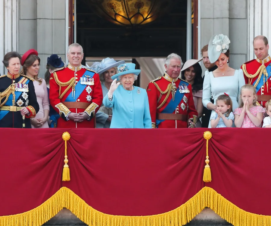 Royal family members on Buckingham Palace balcony, with Queen Elizabeth II in blue, surrounded by family, waving to crowd.