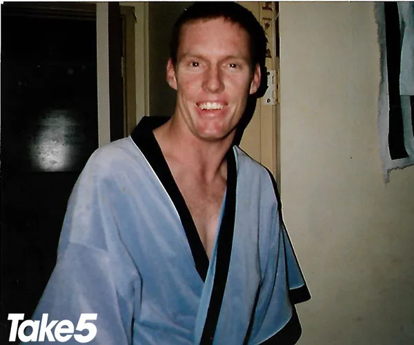 A smiling person wears a blue robe in a room, with a "Take 5" logo at the bottom left corner.