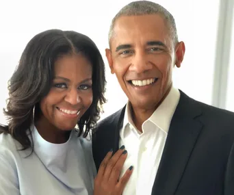 A couple smiling warmly at the camera, with the woman resting her hand on the man's chest.