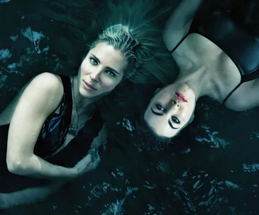 Two women in dark swimsuits floating in water, facing the camera, from the series "Tidelands."