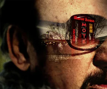 A close-up of a person's face with a motel sign reflecting in their sunglasses.