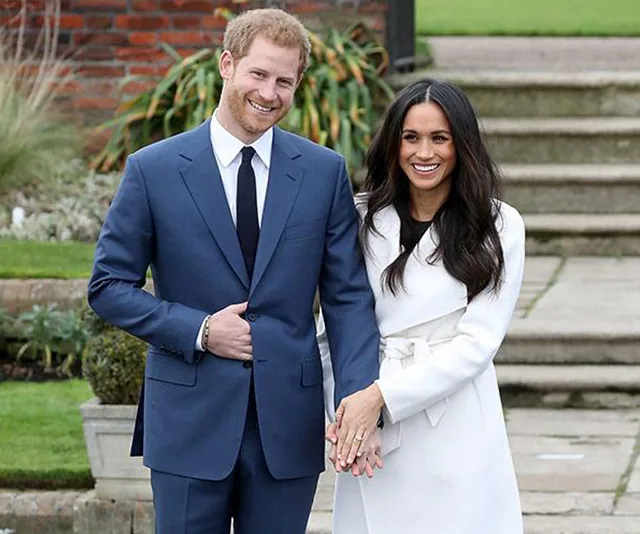 Prince Harry and Meghan Markle smiling and posing outdoors during their engagement announcement event.