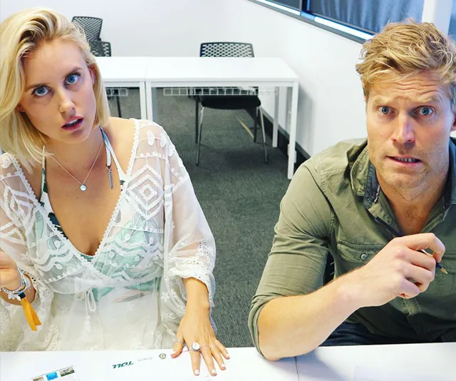 Two people sitting at a table, both looking surprised or confused, with papers in front of them.