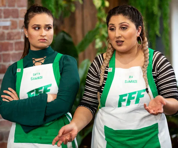 Samadi sisters from "Family Food Fight" wearing aprons, one speaking energetically while the other crosses her arms.