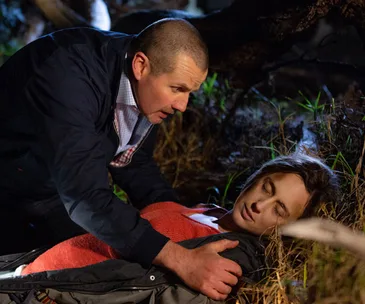 Man urgently attends to an unconscious woman lying on the ground in an outdoor setting.