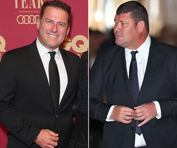 Man in suit at red carpet event next to another man in suit.