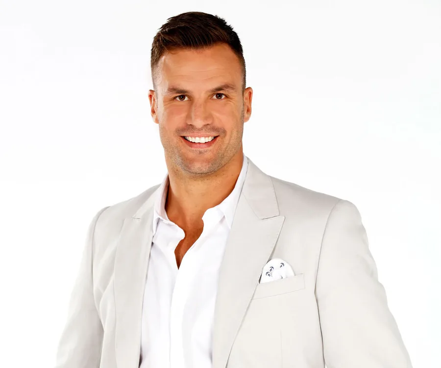 Man smiling in a light gray suit with a white shirt; isolated on white background.