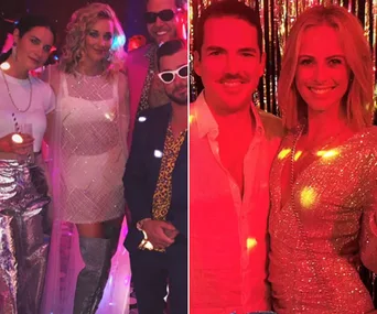 A group of people in glamorous outfits at a Studio 54 themed party, standing and smiling under red and glittering lights.
