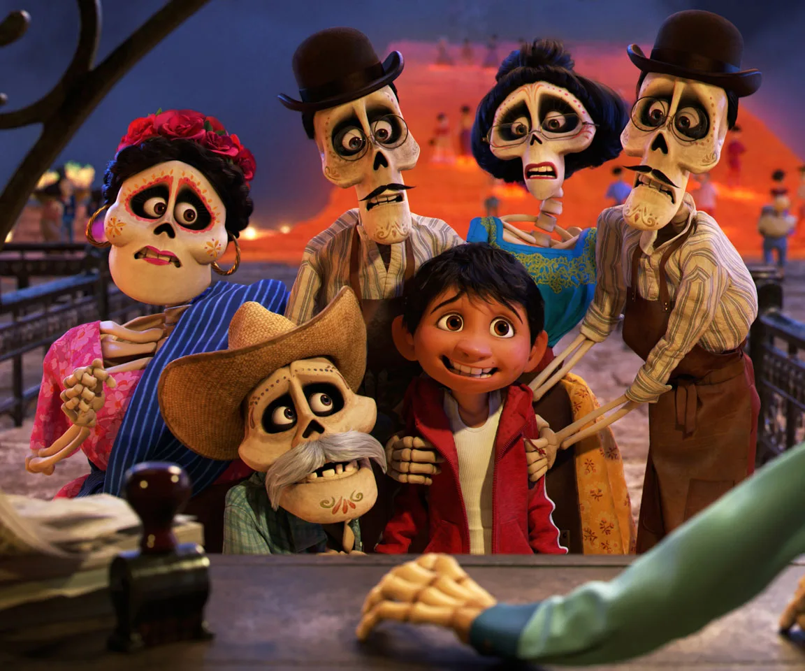 Miguel with skeletal relatives in colorful attire at the Land of the Dead, scene from Disney's "Coco."