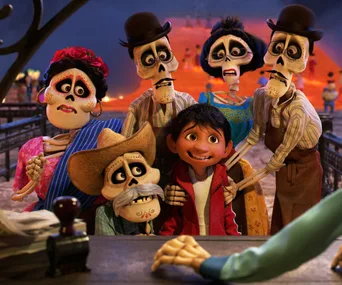 Miguel with skeletal relatives in colorful attire at the Land of the Dead, scene from Disney's "Coco."