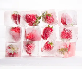 Ice cubes with frozen strawberries stacked in a grid pattern.