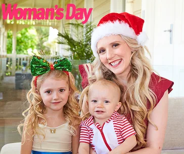 A woman in a Santa hat with two children, smiling indoors, featured in Woman's Day.
