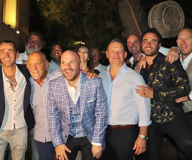 Group of people smiling and posing together at a nighttime outdoor event.