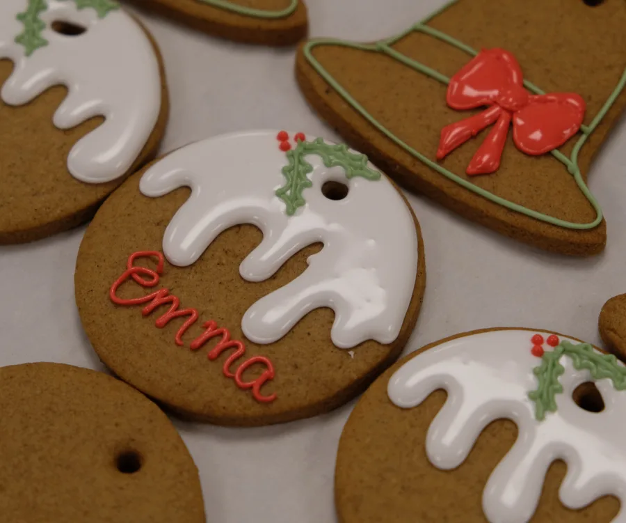 Gingerbread cookies with white icing, holly decorations, and "Emma" piped in red icing.