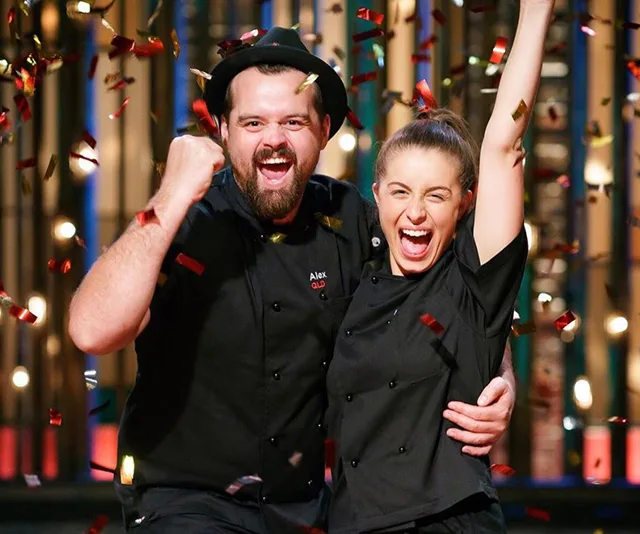 Two chefs celebrate with confetti falling, wearing black uniforms and smiling excitedly.