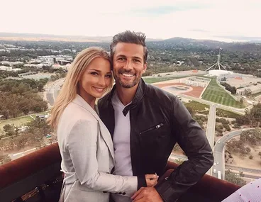 Couple smiling and embracing with a cityscape view in the background.