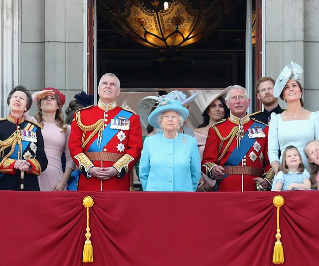 Royal family members on a balcony during a formal event, dressed in military and formal attire, with onlookers below.