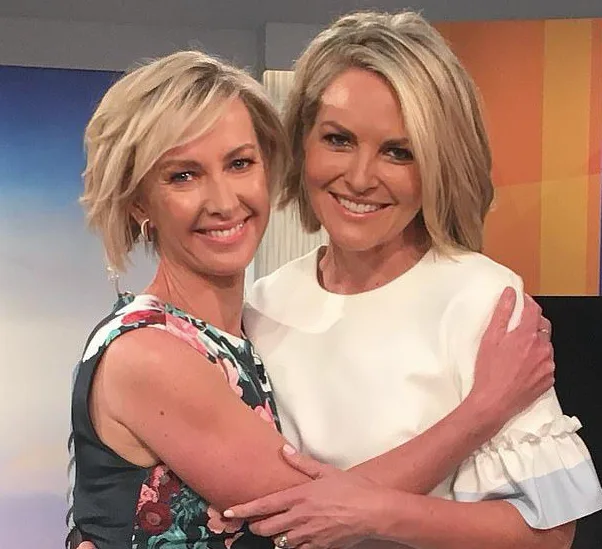 Two women smiling and hugging each other on a television set.