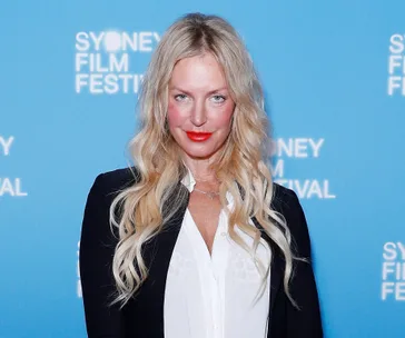 Blonde woman with long hair and red lipstick at Sydney Film Festival in formal attire.