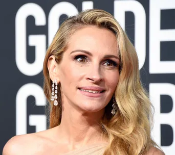 A woman with long blonde hair and diamond earrings at the Golden Globes event.