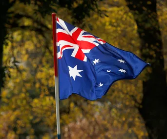 Australian flag waving in the wind with trees in the background.
