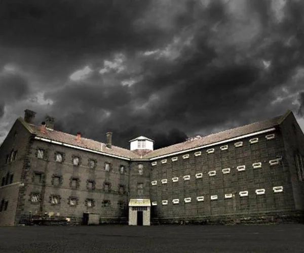 Old Melbourne Gaol under dark, ominous clouds, showcasing its historic, eerie architecture.