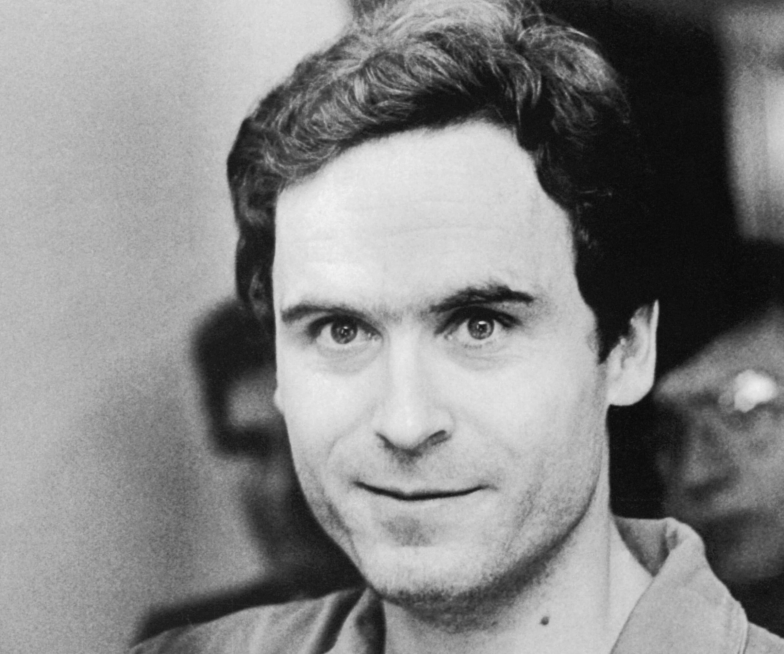 A black-and-white portrait of a man with short hair, looking directly at the camera with a slight smile.