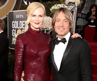 A couple posing together on the red carpet at a formal event, both dressed elegantly in evening attire.