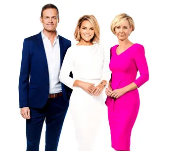 Three individuals in professional attire posing together: one in a suit, one in a white dress, one in a pink dress.