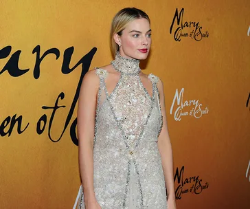 A woman in a beaded gown stands in front of a "Mary Queen of Scots" backdrop.