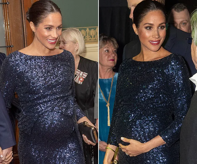 Pregnant woman in a blue sequined dress, smiling and holding a clutch at an event with people in the background.